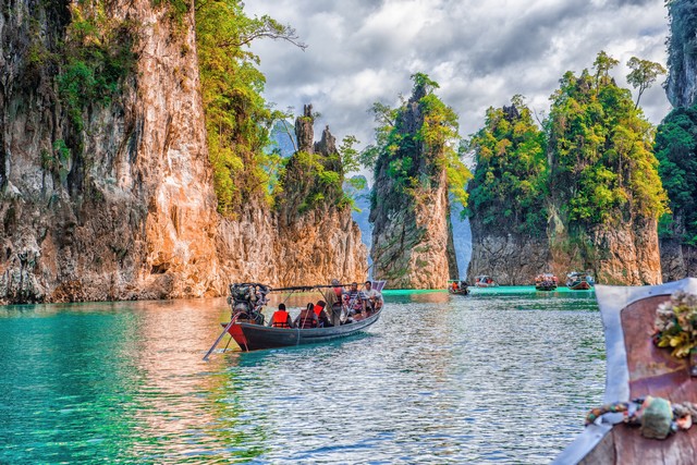 Tourists riding a boat to see the beauty of the rock cliff