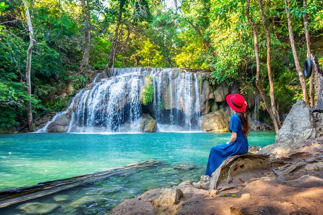 Woman sitting at waterfall in Thailand
